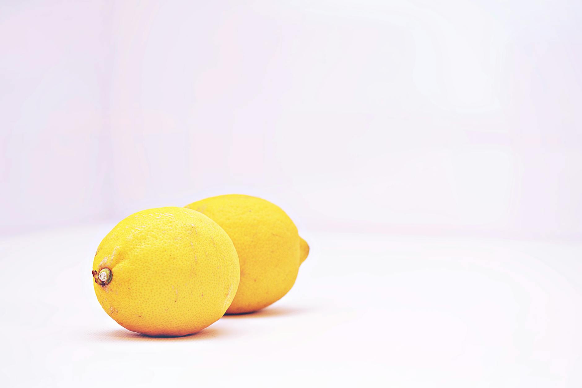 Bright yellow lemons arranged on a pastel green background, creating a fresh and vibrant flat lay composition.