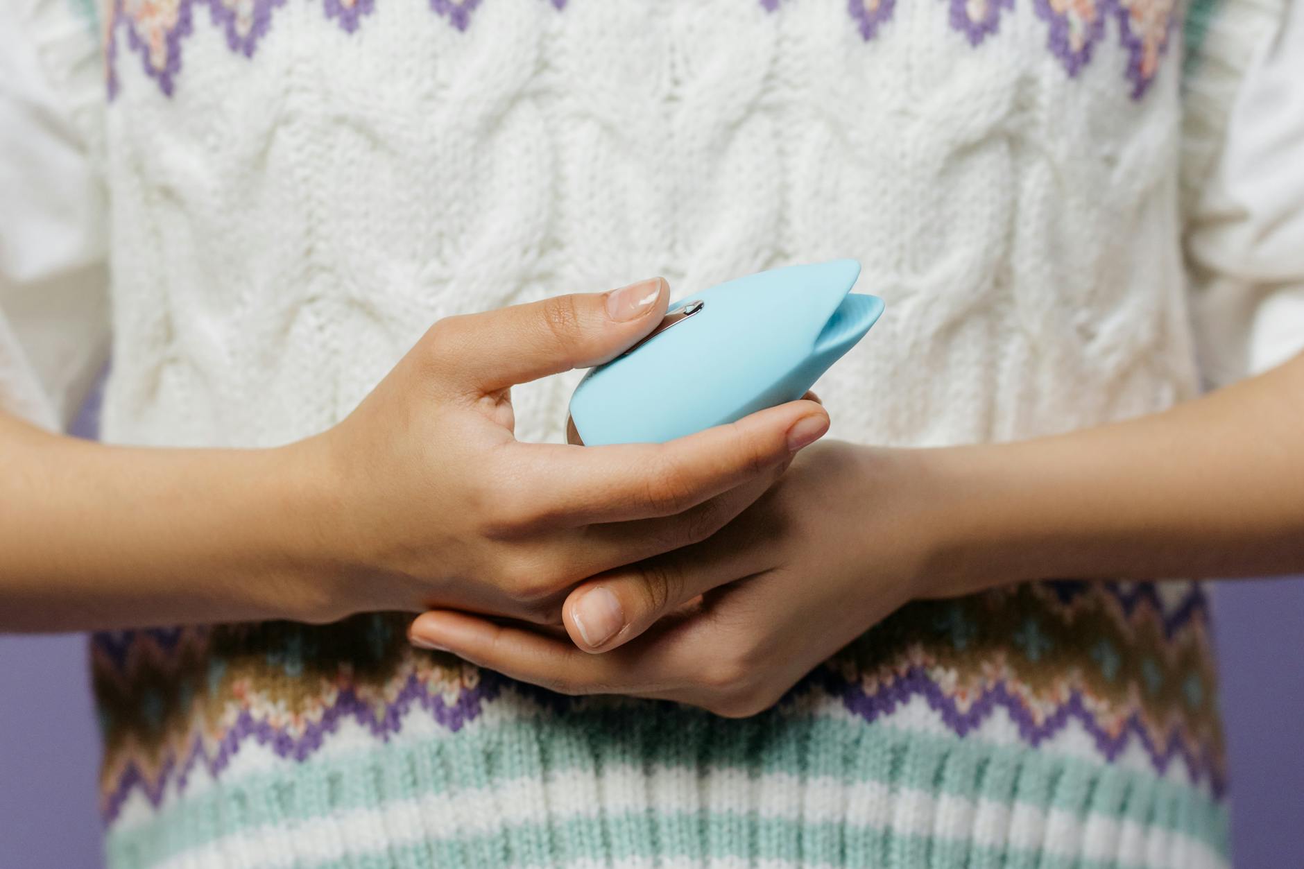 Close-up of hands holding a personal massager, showing how couples can navigate mismatched arousal timing.