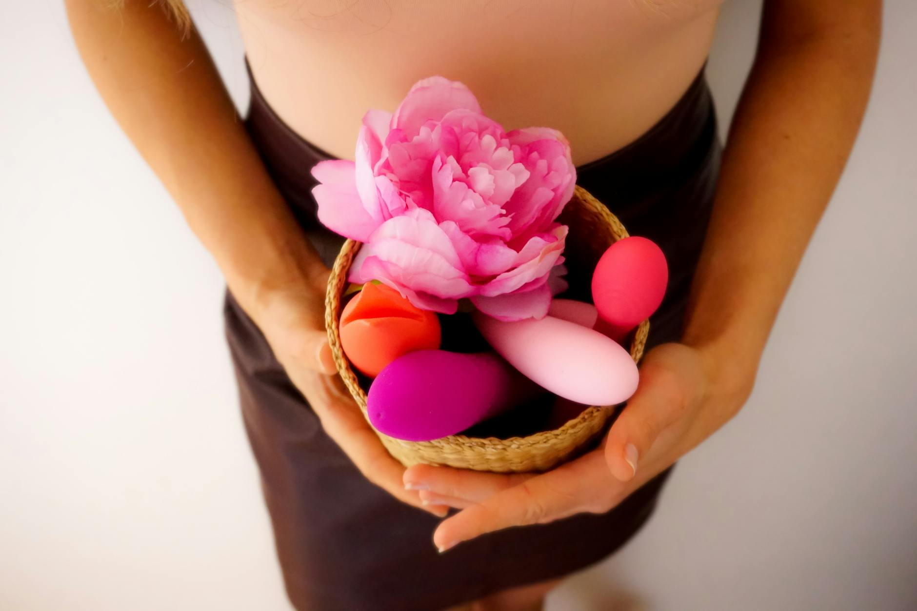 A woman holding a silicone vibrator with a thoughtful expression